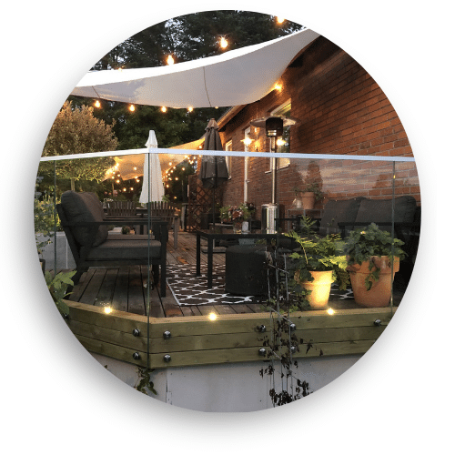 Terrasse en bois cosy avec garde-corps en verre transparent et éclairage décoratif, parfaite pour des soirées en plein air.