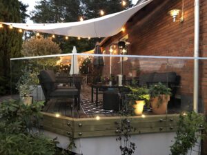 Garde-corps en verre monté sur une terrasse en bois avec éclairage LED intégré et coin salon extérieur chaleureux.