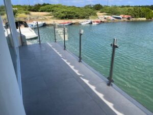 Garde-corps en acier inoxydable installé le long d’un ponton – vue sur petits bateaux et verdure.