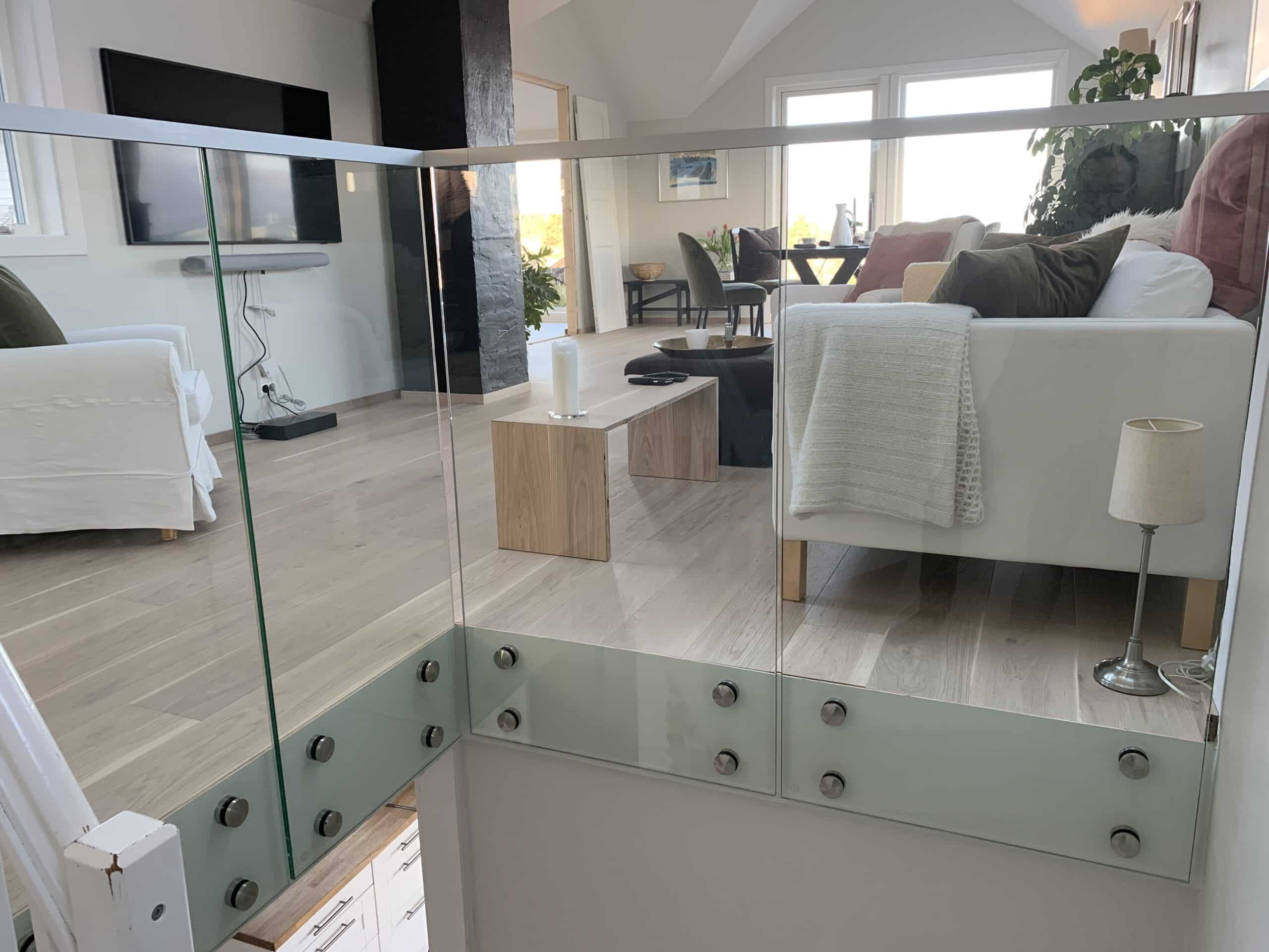 Balustrade intérieure en verre sans cadre avec fixations acier brossé, sécurisant ouverture d’escalier dans loft lumineux.